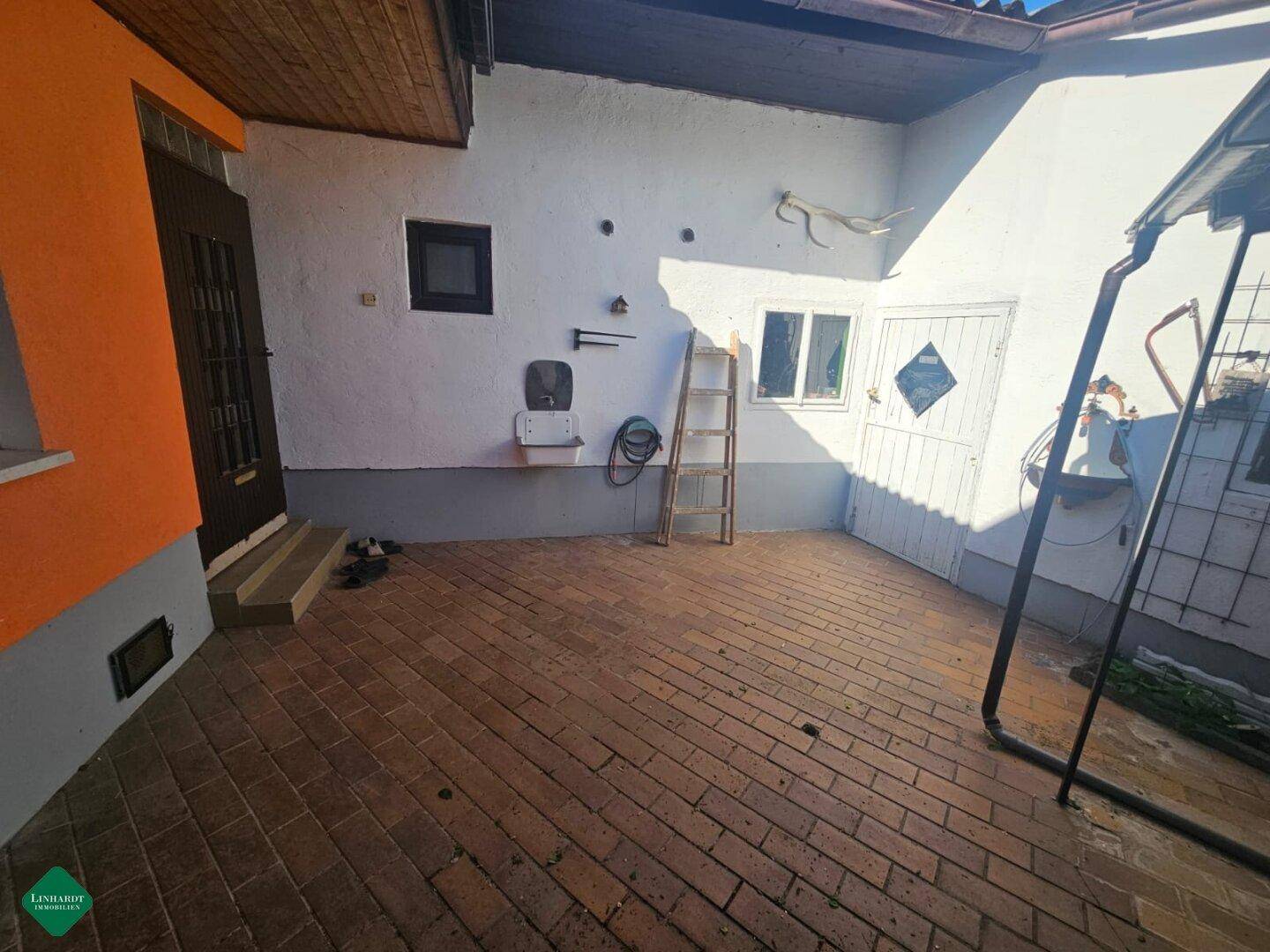 Gepflasterter Innenhof mit weiß getünchten Wänden und Zugang zu verschiedenen Räumen des Hauses.
