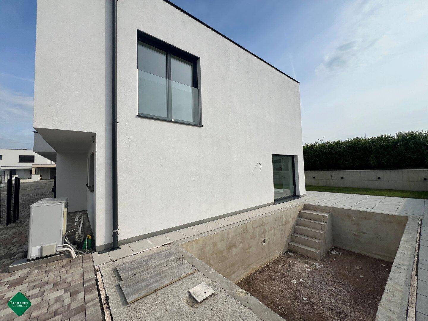 Seitenansicht des Hauses mit Zugang zum Keller und einer Außeneinheit für Heizung oder Klimaanlage.