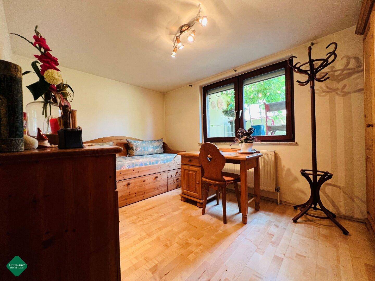 Helles Schlafzimmer oder Gästezimmer mit Tagesbett, Holzschreibtisch und Garderobenständer.