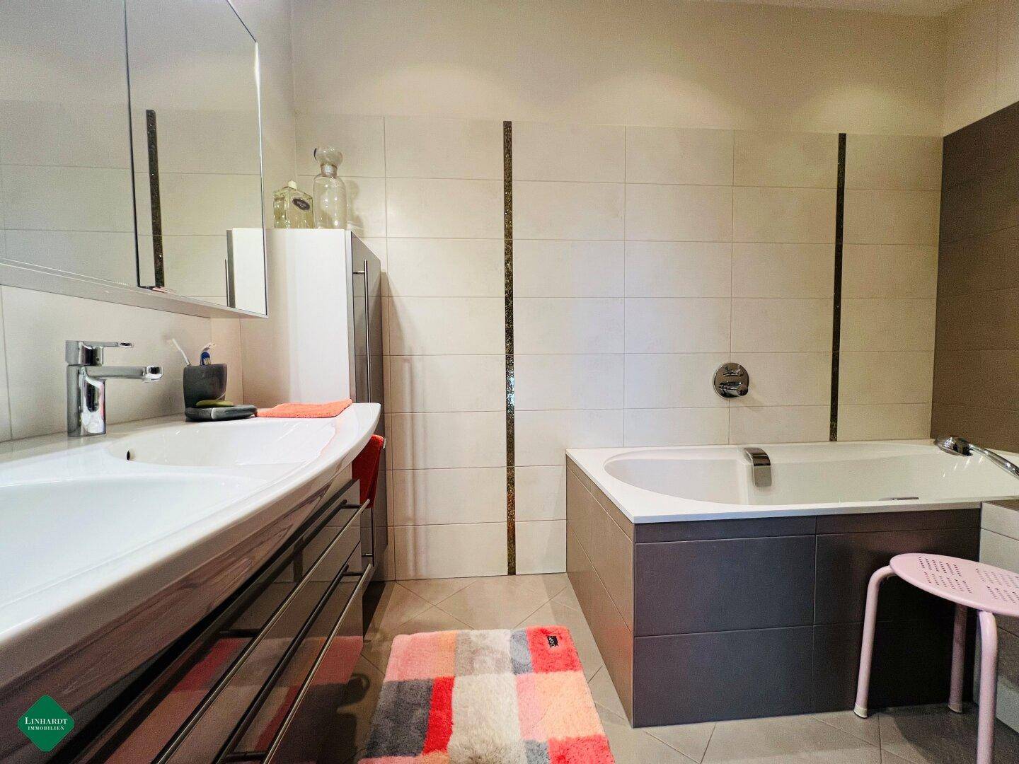 Modernes Badezimmer mit Einzelwaschbecken, Badewanne und großformatigen Fliesen.