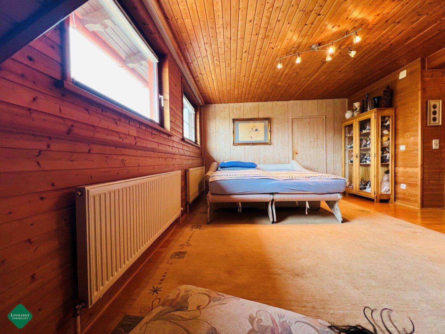 Gemütliches Schlafzimmer mit Holzverkleidung an Wänden und Decke sowie Teppichboden.