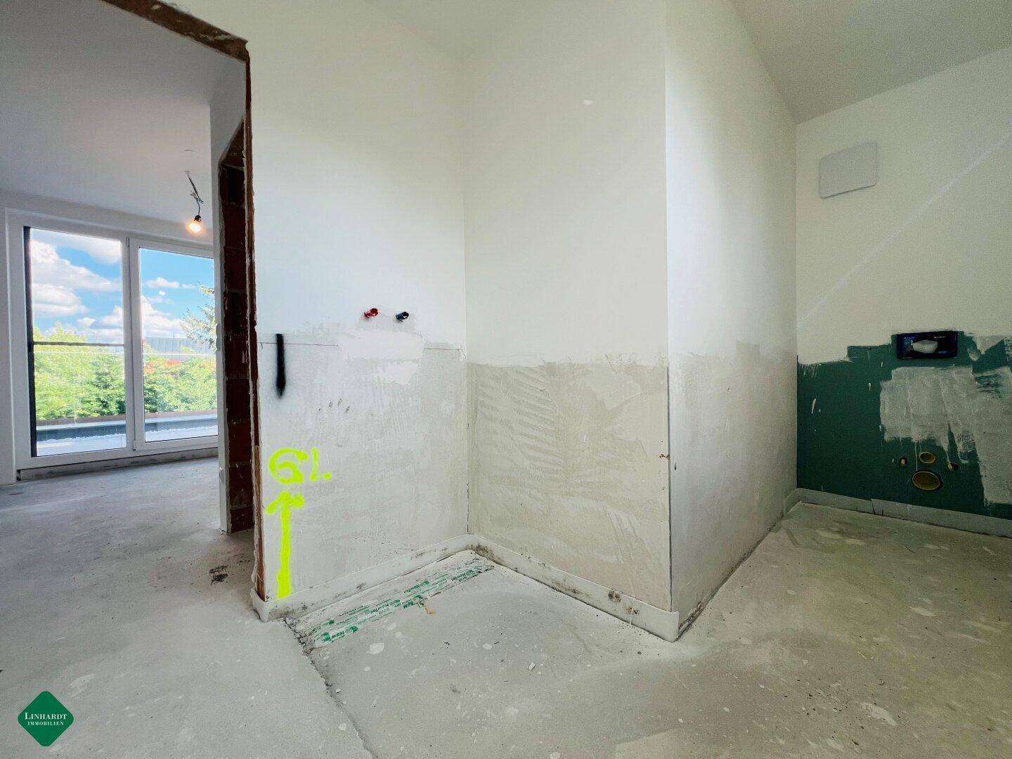Badezimmer im Rohbau mit vorbereiteten Wänden und sichtbaren Installationen für Sanitäranlagen.