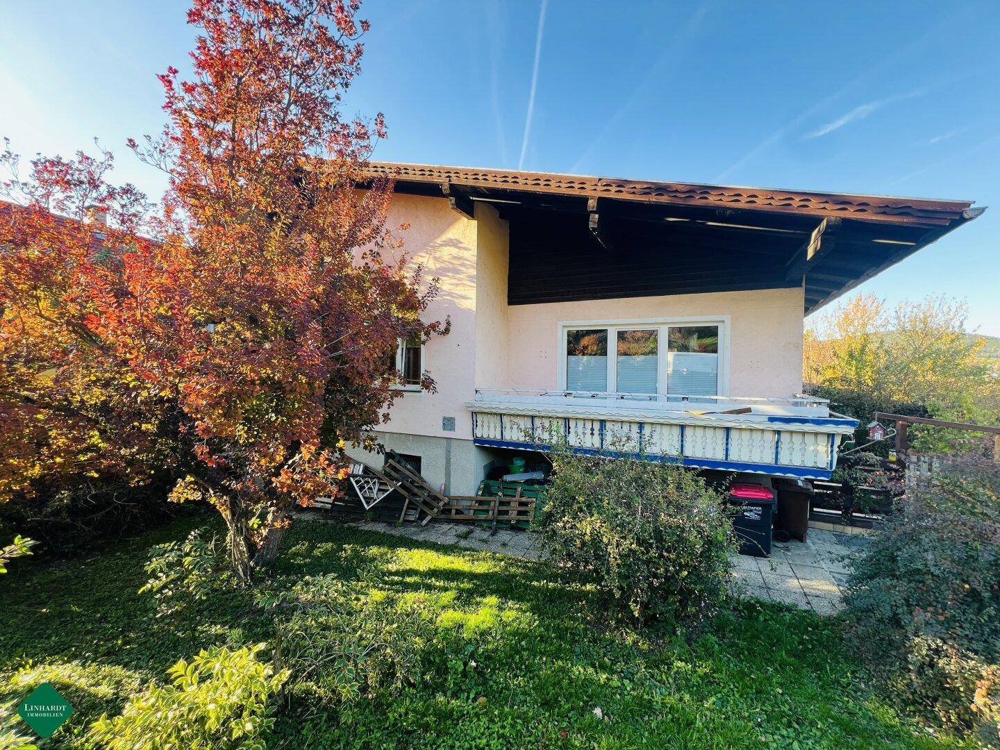 Rückansicht eines Hauses mit Gartenbereich und Herbstbäumen unter klarem Himmel.
