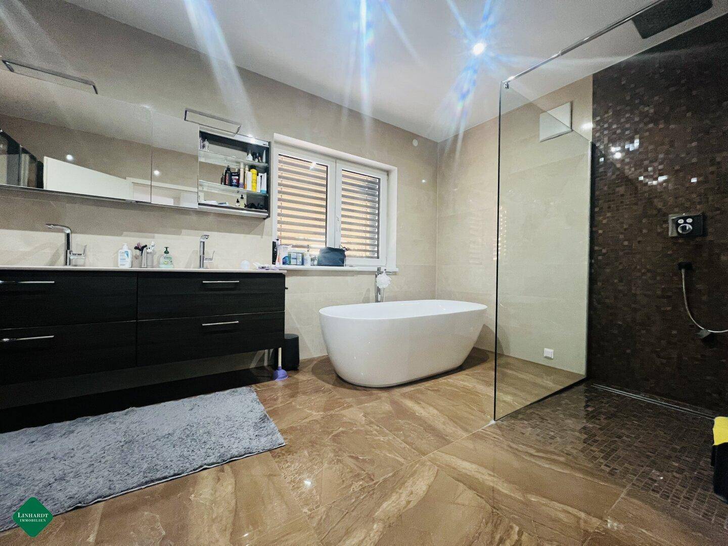 Elegantes Badezimmer mit freistehender Badewanne, großer begehbarer Dusche und Doppelwaschbecken.