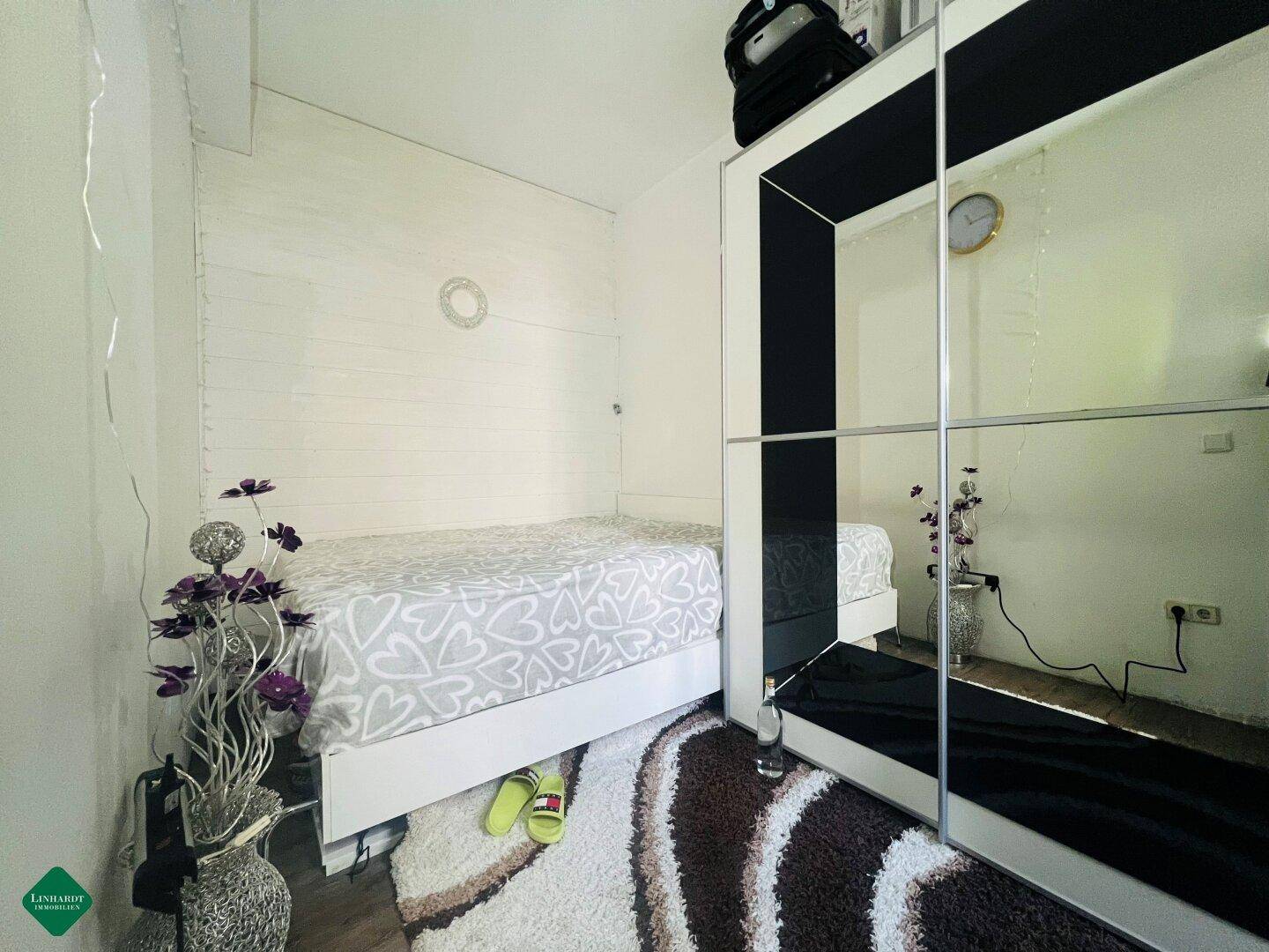 Kleines Schlafzimmer mit Einzelbett, Spiegelschrank und Holzwänden.