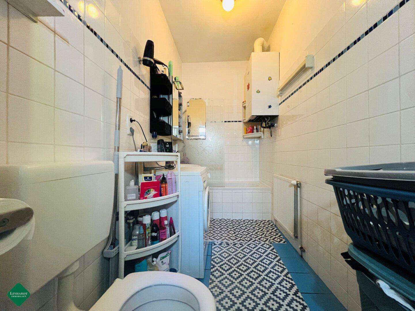 Gefliestes Badezimmer mit Badewanne, Toilette und Waschmaschine.