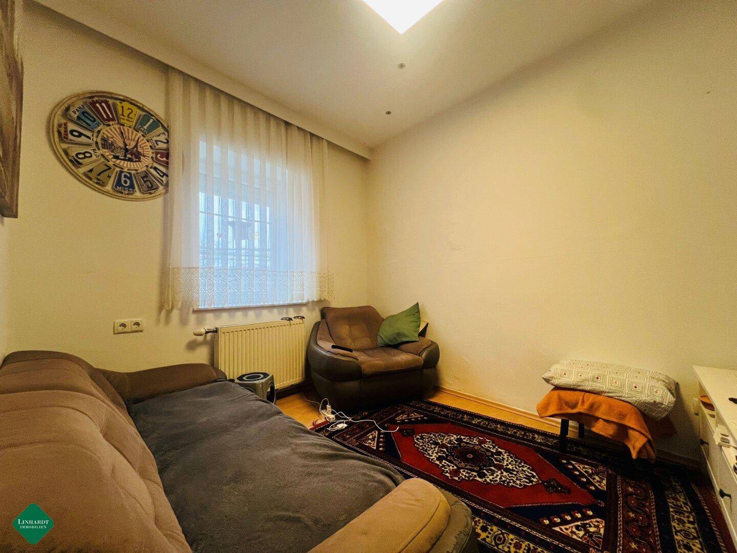 Gemütliches Zimmer mit Sofa, Sessel und Holzboden, ideal als Gästezimmer oder Arbeitsbereich.