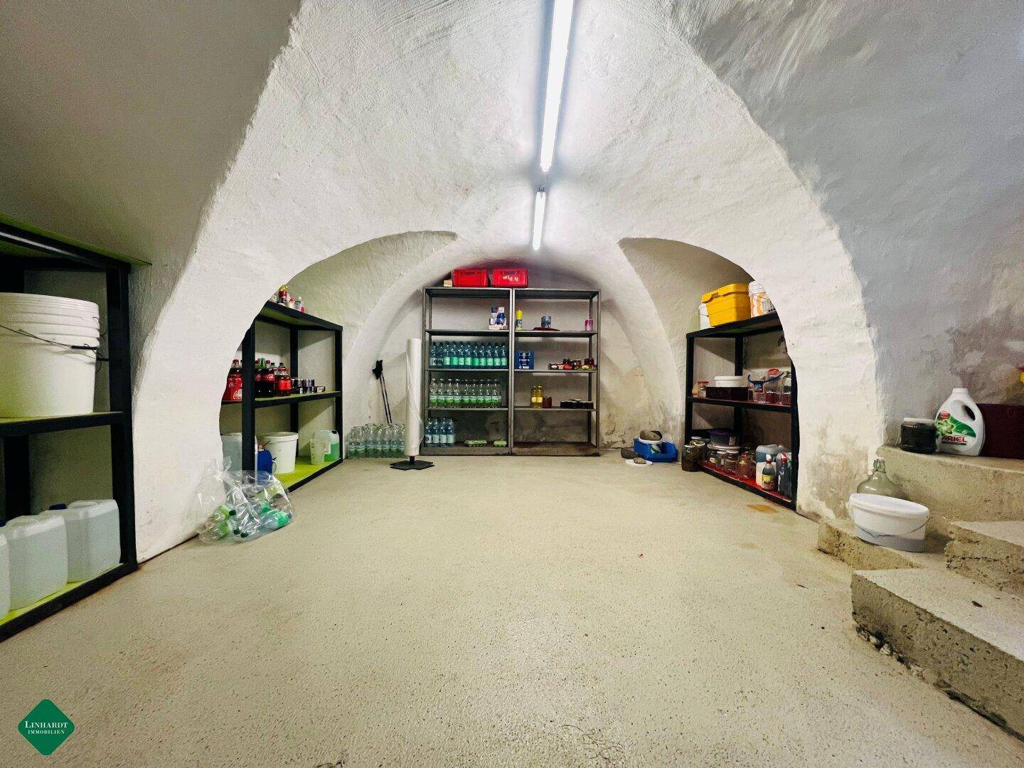 Geräumiger Keller mit Gewölbedecken und Regalen, ideal zur Lagerung von Vorräten und Gegenständen.