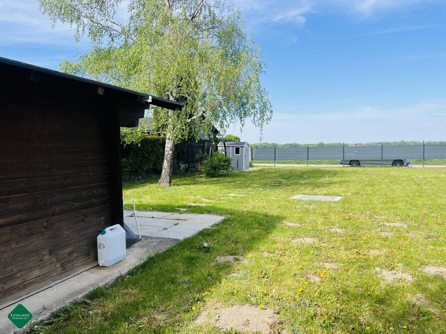 Weitläufiger Gartenbereich neben einem Holzhaus mit Blick auf die offene Landschaft.