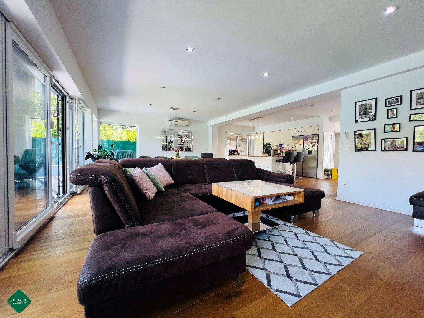Gemütliches Wohnzimmer mit großem Sofa und Zugang zur Terrasse durch breite Glasfronten.