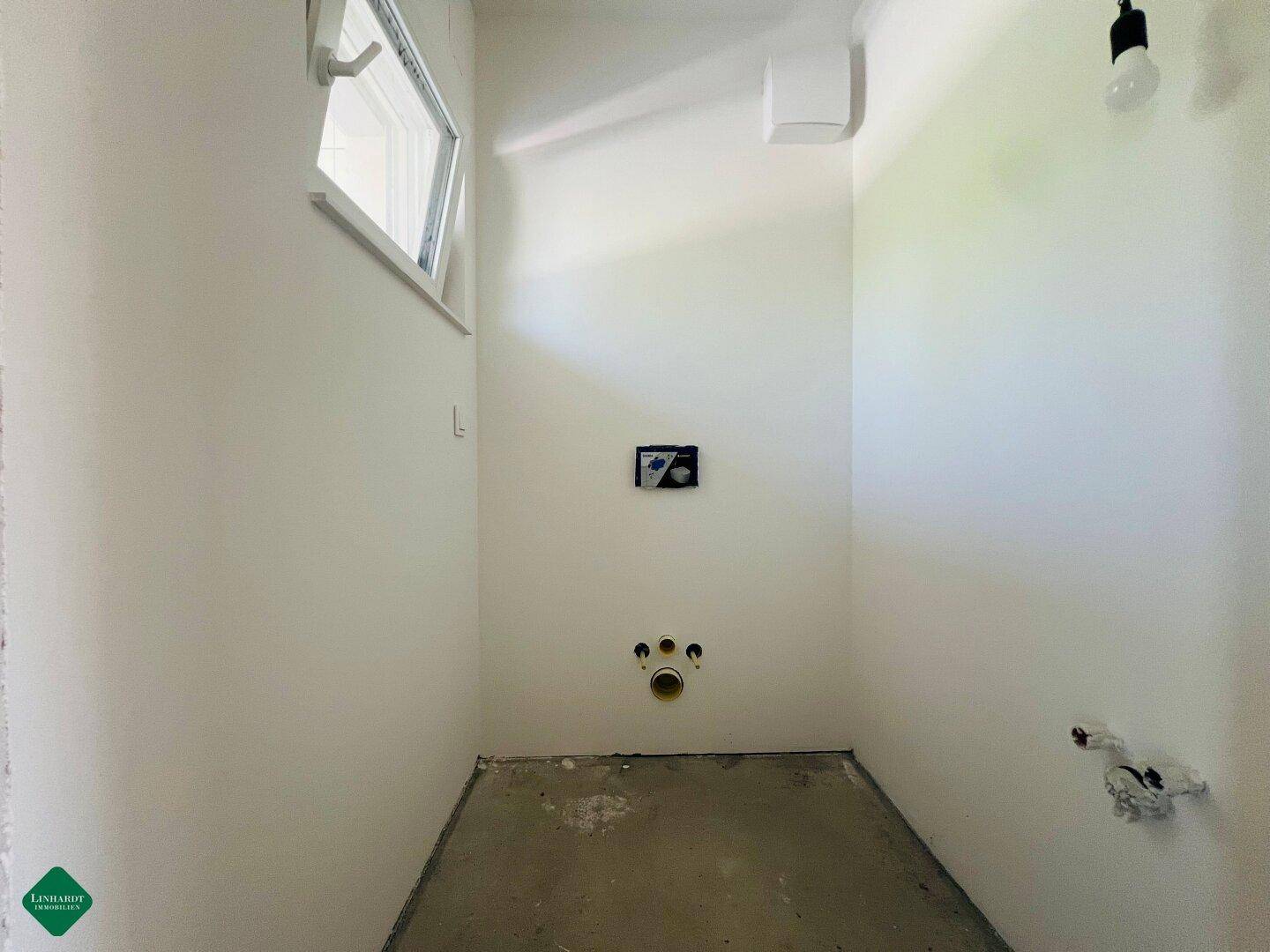 Kleiner, unfertiger WC-Raum mit Fenster und vorbereiteten Sanitäranschlüssen.