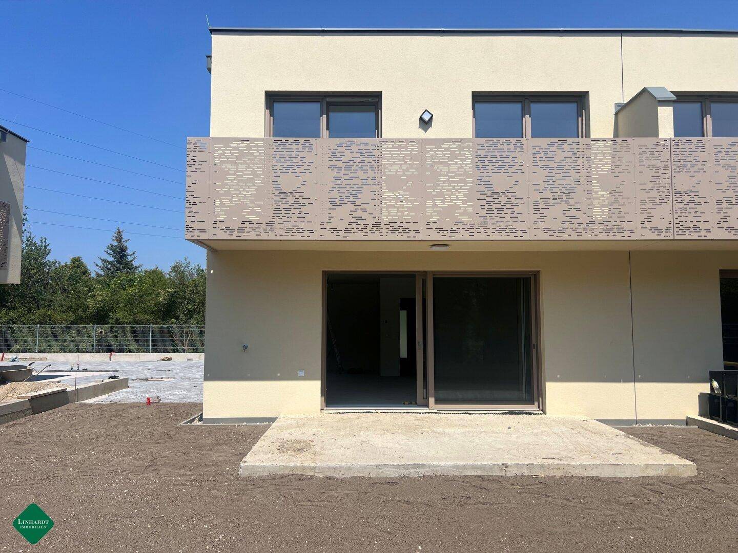 Nahaufnahme der modernen Fassade mit großen Schiebetüren und Balkon im Obergeschoss.