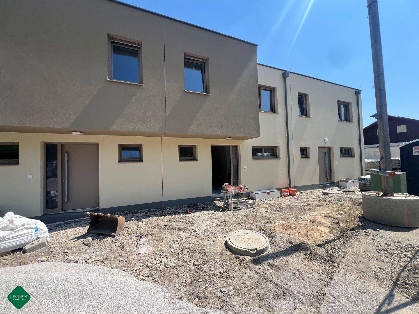 Außenansicht eines modernen Neubaus mit mehreren Eingängen und unfertigem Vorplatz.