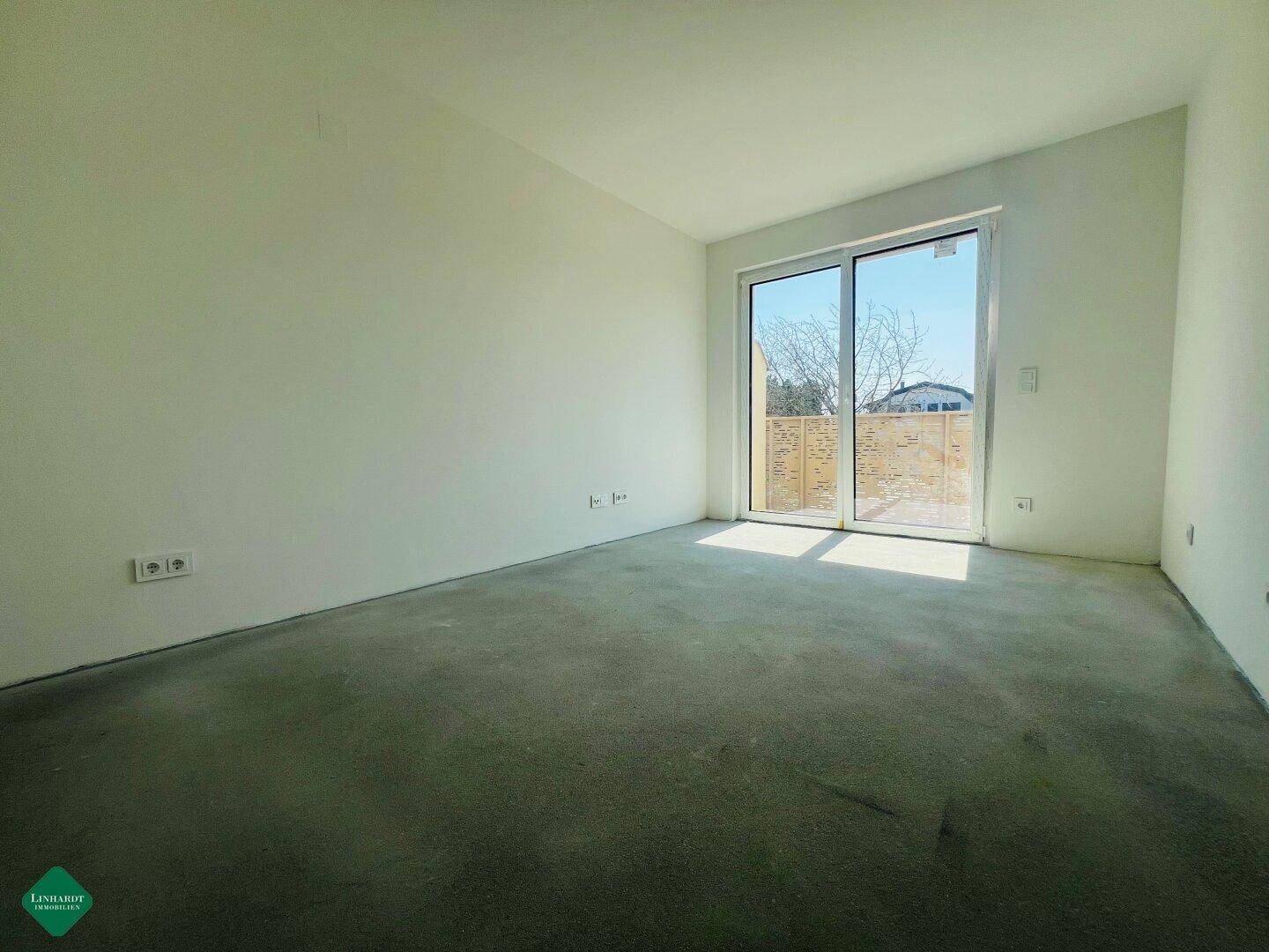 Unmöbliertes Zimmer mit großen Fenstern und hellem Lichteinfall im Neubau.