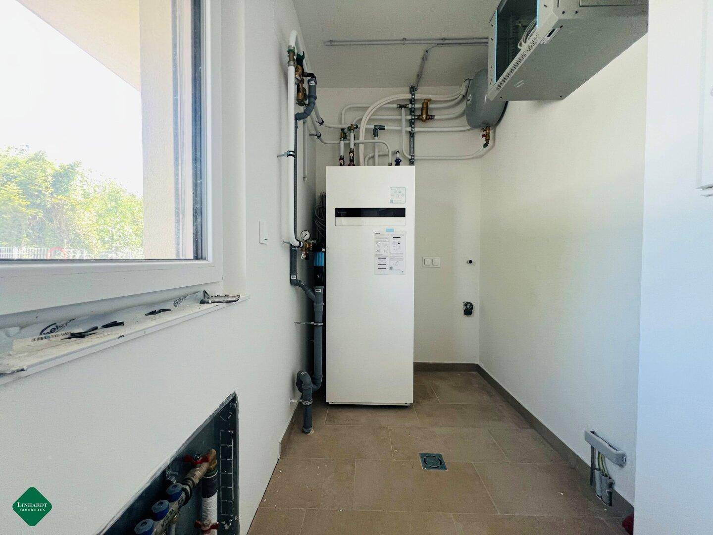 Technikraum mit moderner Wärmepumpe und sichtbaren Installationen, bereit für den Betrieb.