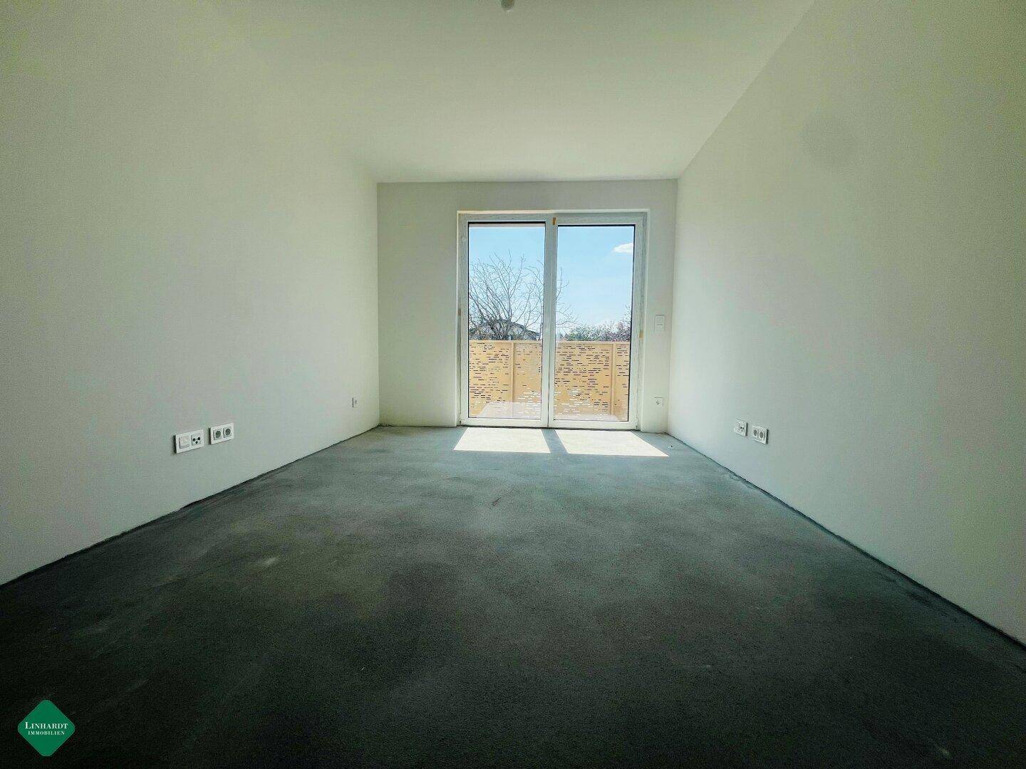 Heller Raum im Rohbau mit Schiebetür und Blick auf den Außenbereich, bereit für den Ausbau.