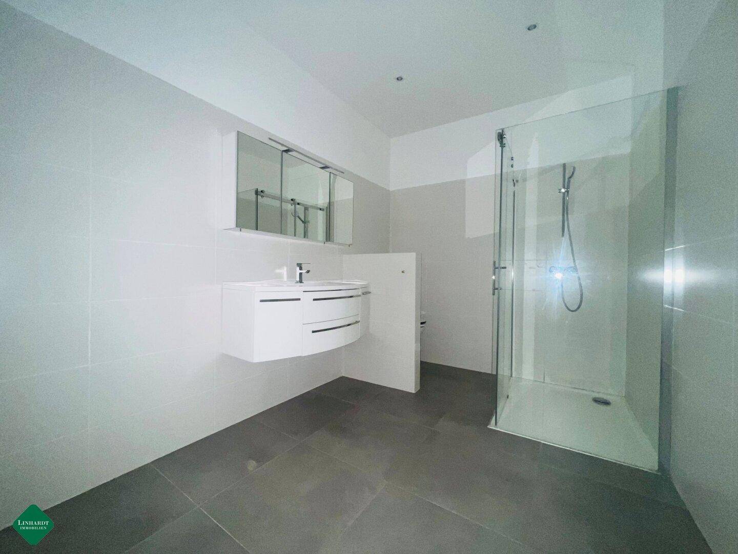 Modernes Badezimmer mit großer Duschkabine, schwebendem Waschtisch und Spiegelschrank.