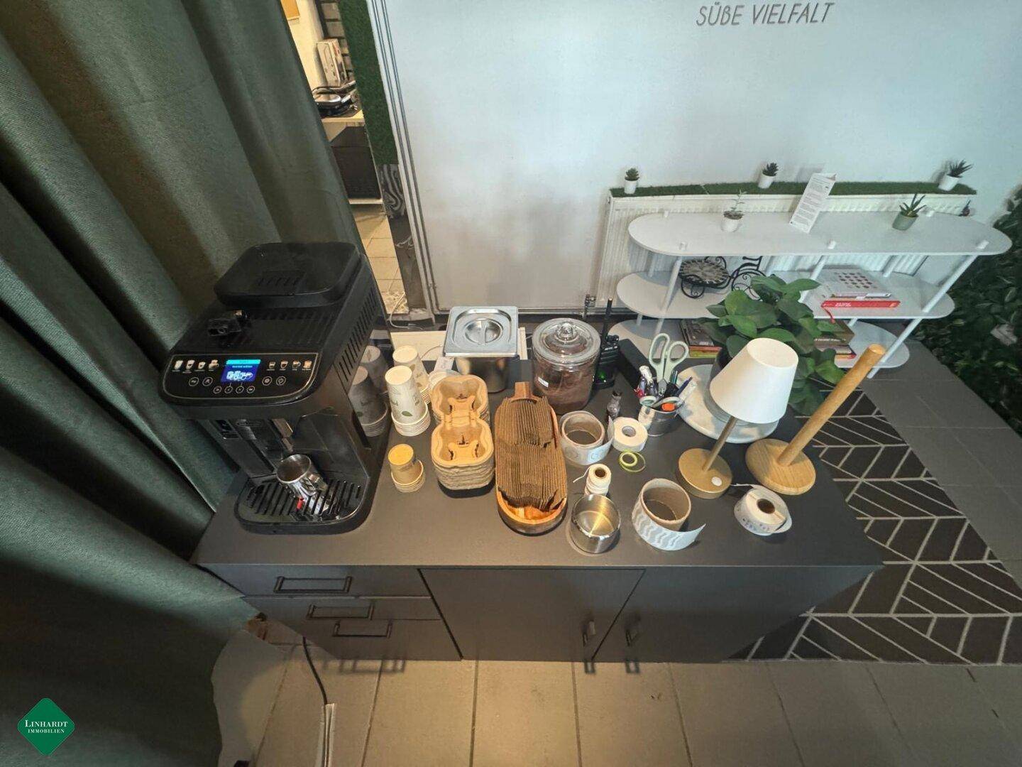 Detailansicht einer Kaffeestation mit professioneller Kaffeemaschine und Zubehör auf dunkler Arbeitsplatte.