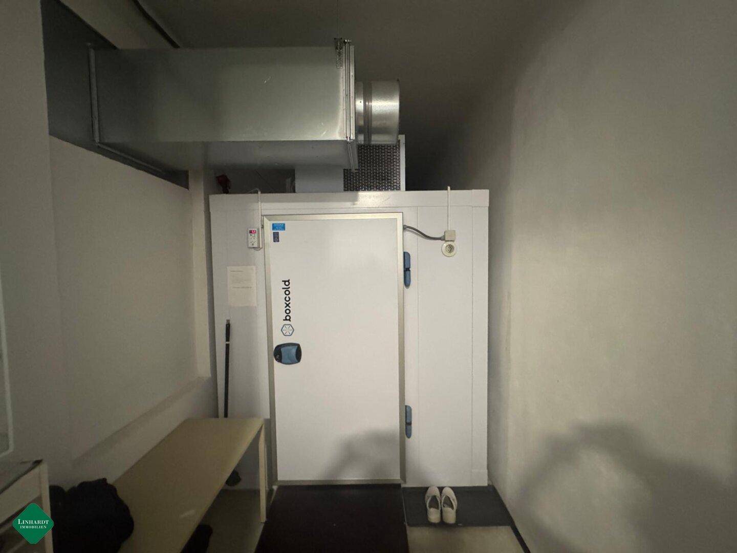 Ein großer Kühlraum mit isolierter Tür und sichtbaren Lüftungsrohren an der Decke für gewerbliche Nutzung.
