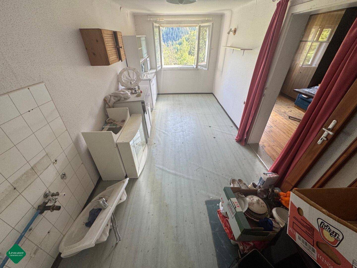 Küche mit alten Fliesen, Fenster und Blick ins Grüne, bereit für eine Modernisierung.