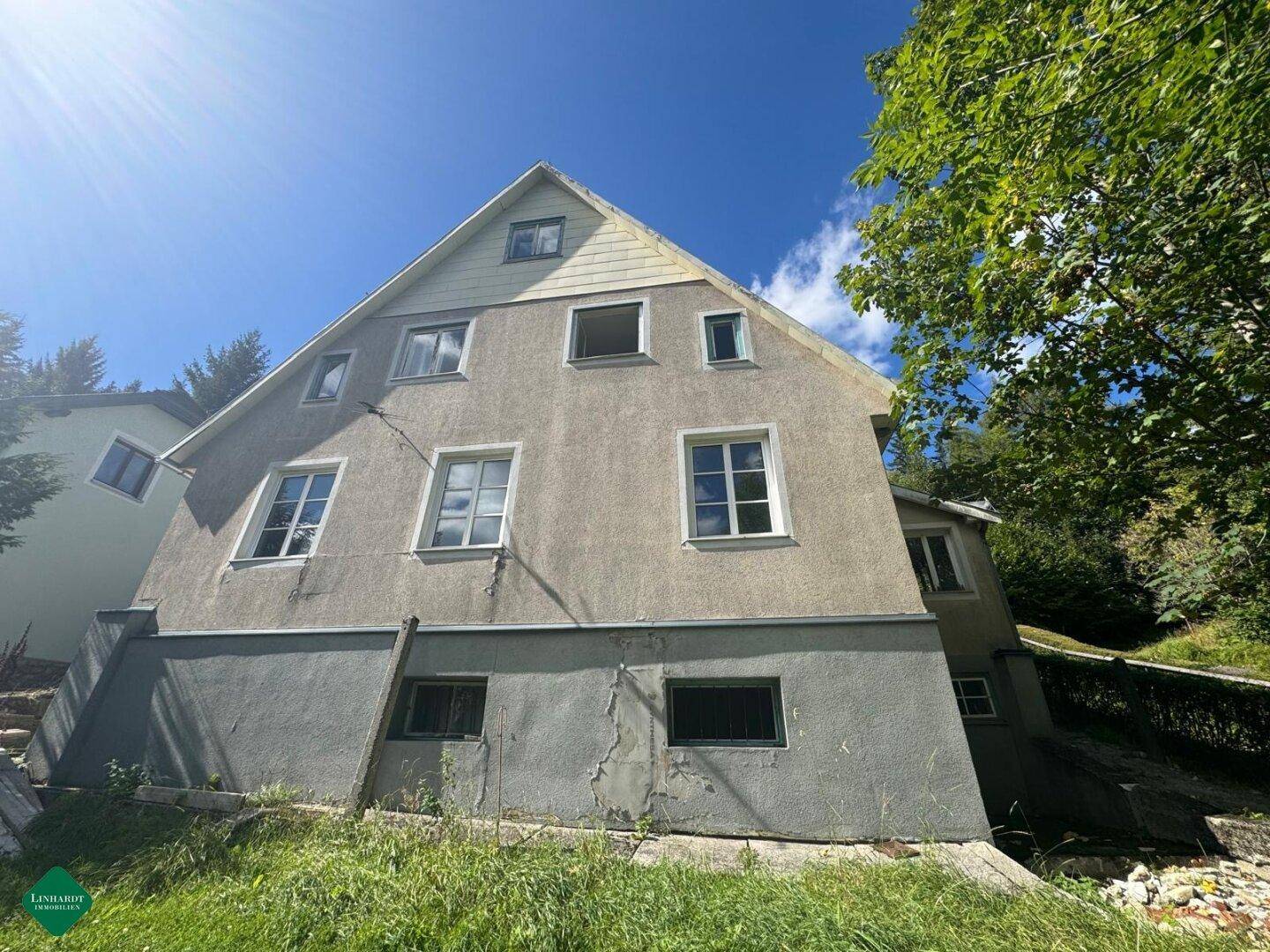 Ansicht des Hauses von der Seite mit mehreren Fenstern und einem Dachgiebel unter blauem Himmel.