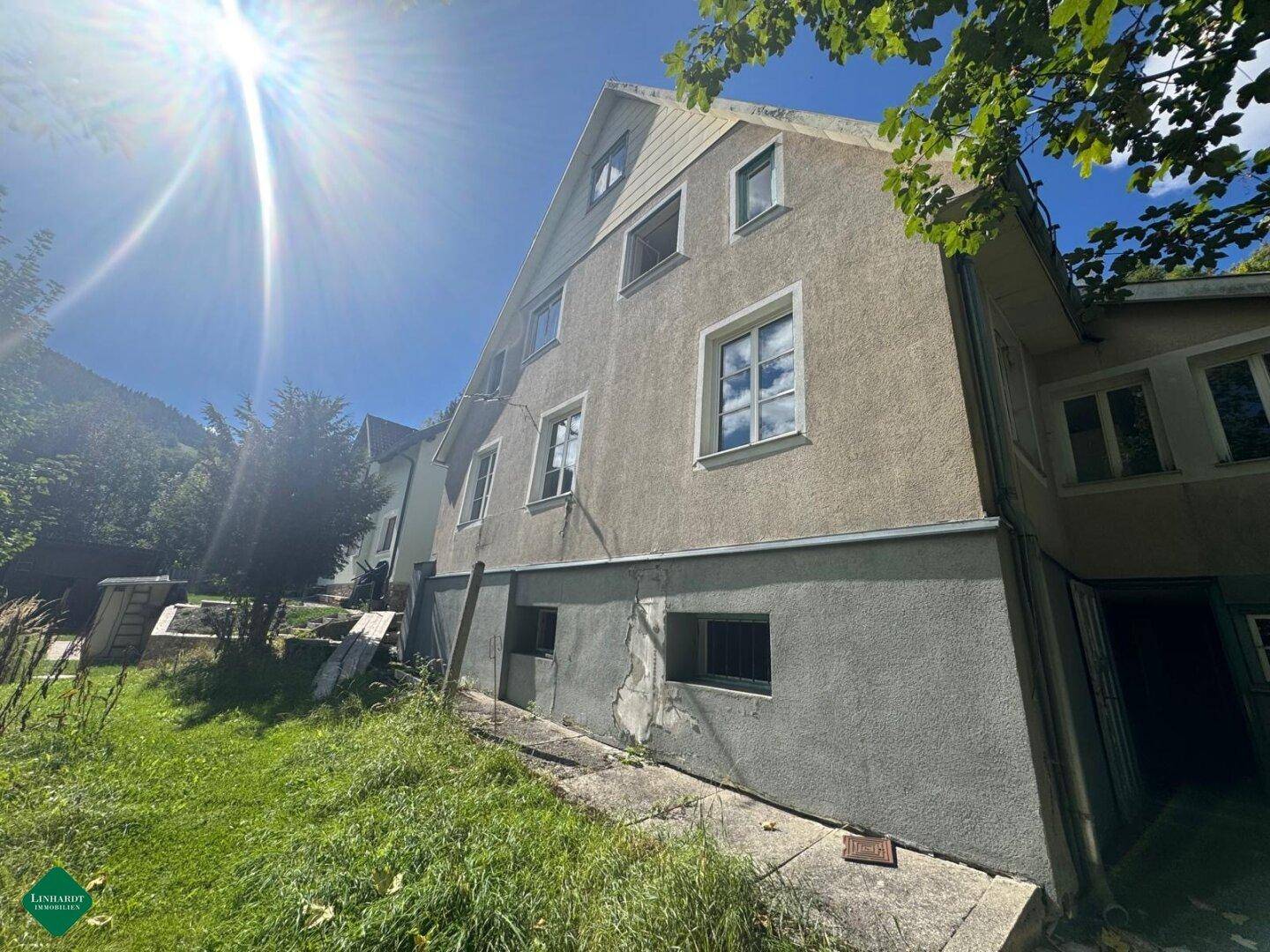 Ansicht des Hauses von der Seite mit mehreren Fenstern und einem Dachgiebel unter blauem Himmel.