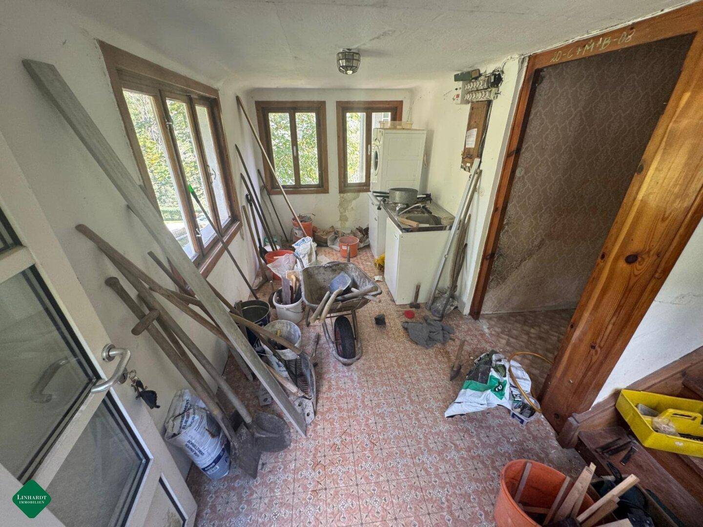 Einfacher Raum mit Fensterfront, Waschmaschine und Spülbecken, als Hauswirtschaftsraum nutzbar.