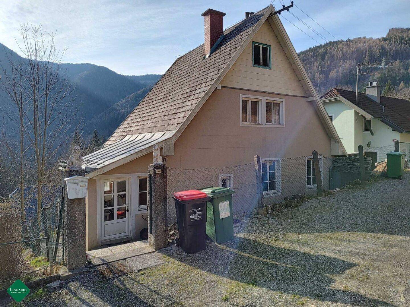 Seitenansicht des Hauses mit Eingangsbereich, Schrägdach und Blick auf die Berge.