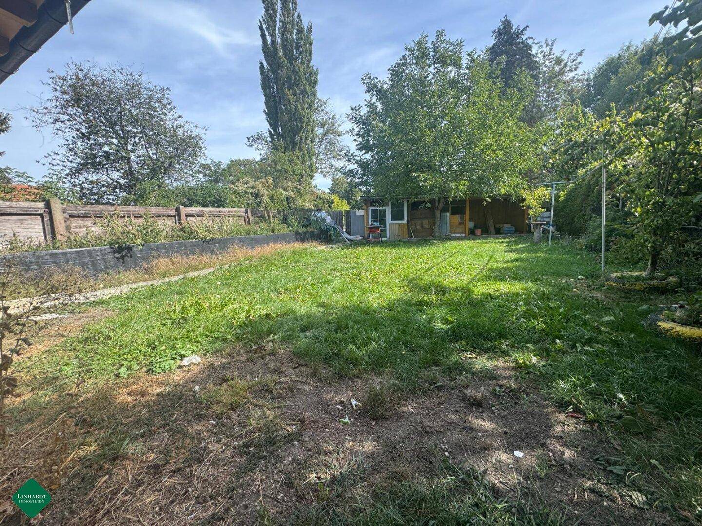 Großer Gartenbereich mit Rasenfläche und Bäumen im Hintergrund, ideal für Erholung im Freien.