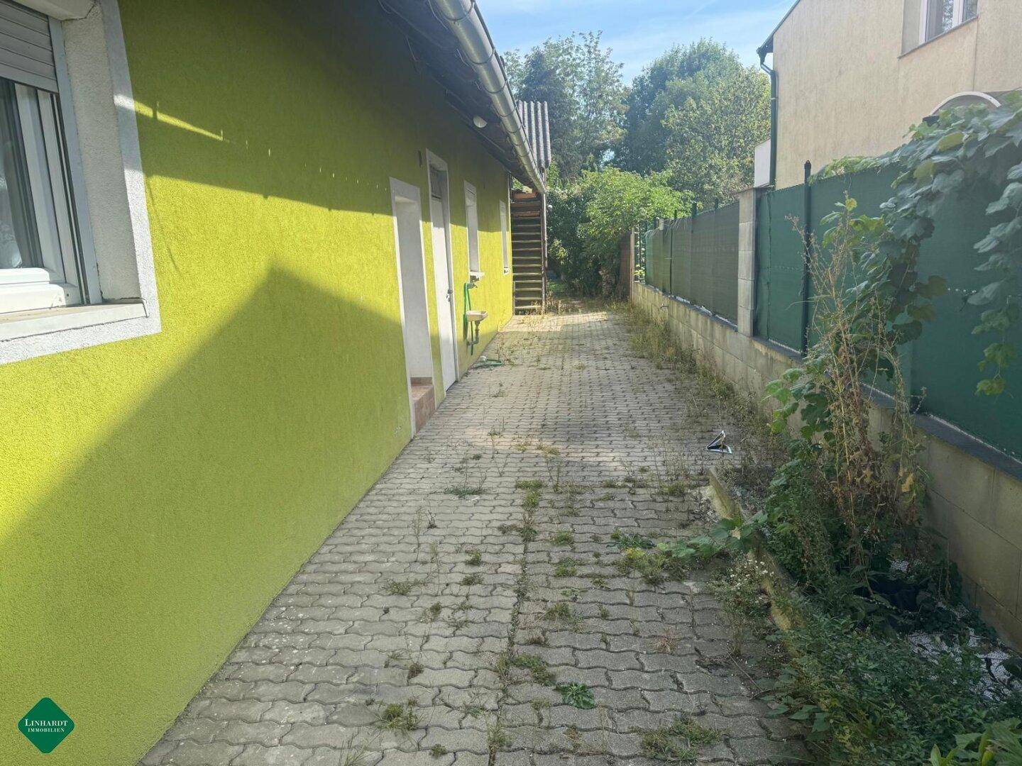 Seitenansicht des Gebäudes mit leuchtend grüner Fassade und gepflastertem Weg.