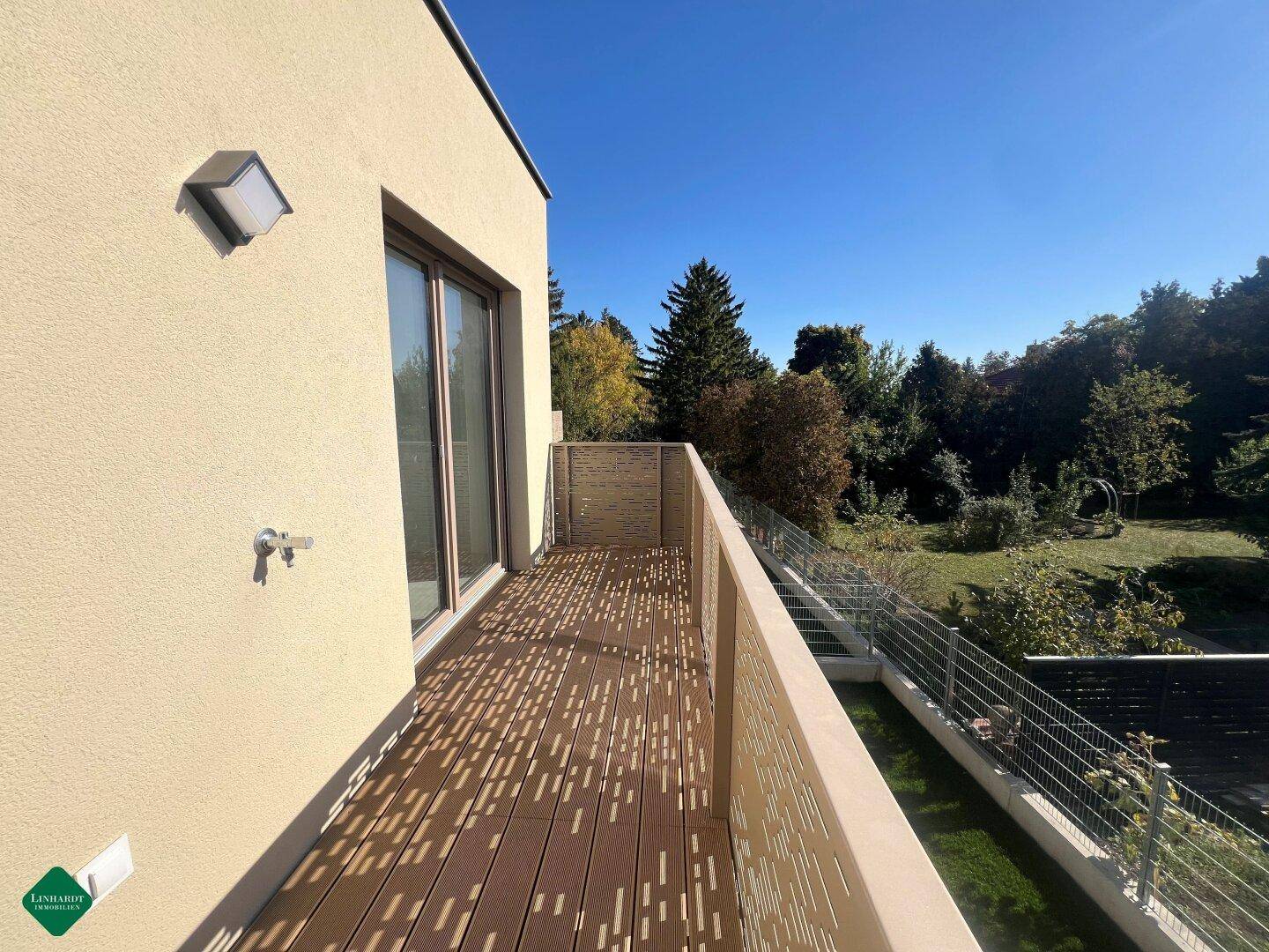 Geräumiger Balkon mit Holzboden und perforierter Brüstung bietet einen schönen Blick ins Grüne.