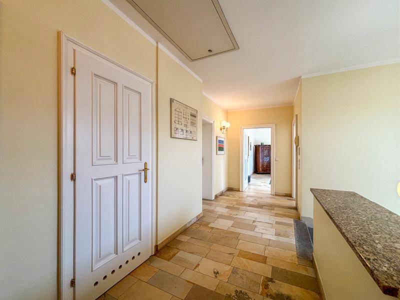 Heller Flur mit Fliesenboden und einer Granitablage, der zu weiteren Räumen führt.