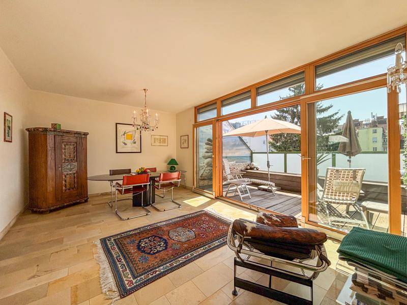 Esszimmer mit Fliesenboden und großen Fenstern, die Zugang zu einer sonnigen Terrasse bieten.