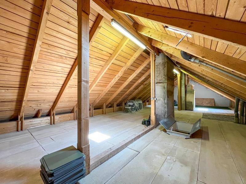 Geräumiger Dachboden mit sichtbaren Holzbalken und -verkleidungen, bereit für den Ausbau.