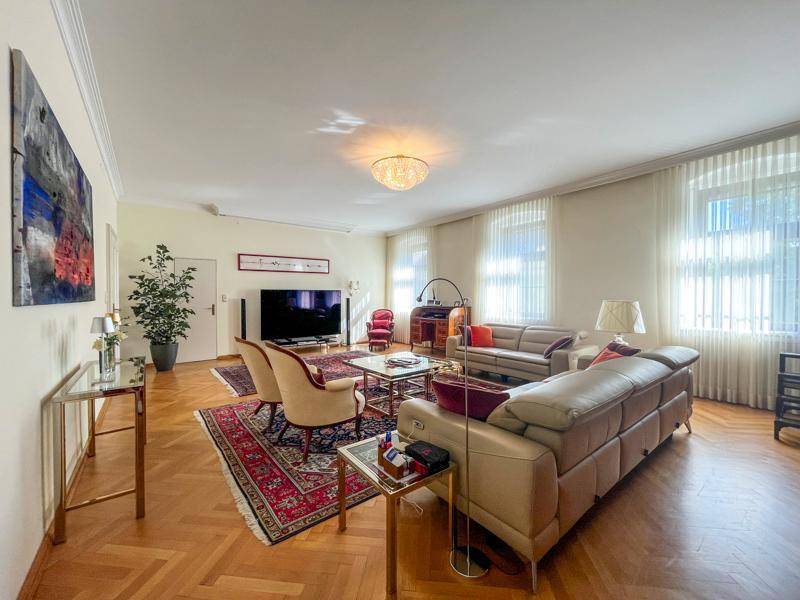 Geräumiges Wohnzimmer mit eleganten Möbeln, Parkettboden und großen Fenstern für viel Licht.