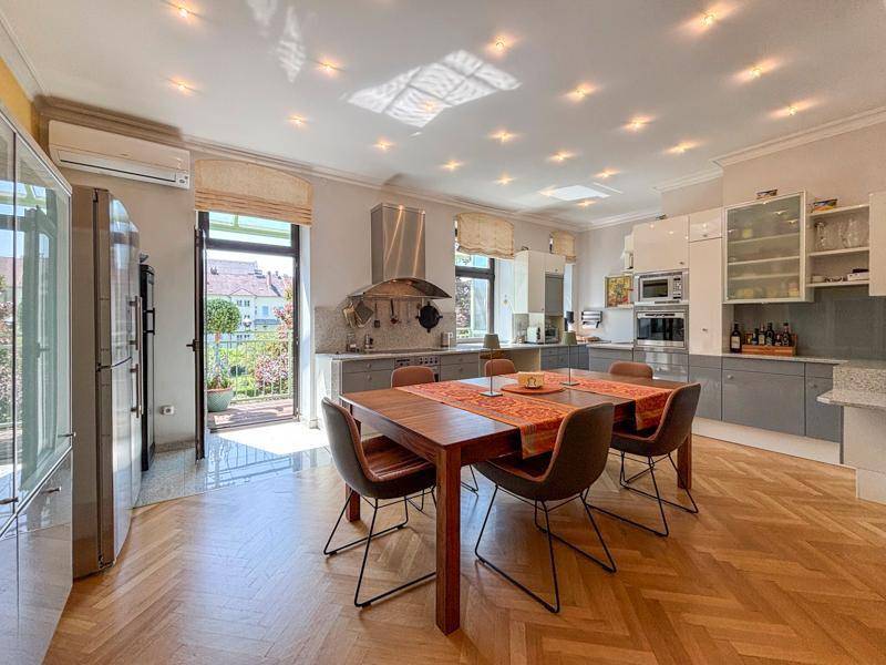 Moderne Küche mit Essbereich, Parkettboden und Zugang zu einem sonnigen Balkon.