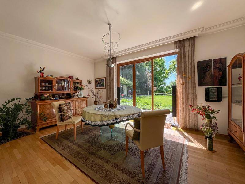 Gemütlicher Essbereich mit Holzboden, traditionellen Möbeln und großem Fenster zum Garten.