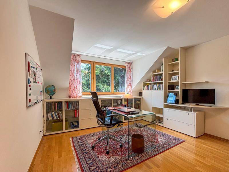 Helles Arbeitszimmer mit Dachschräge, Holzfußboden und integrierten Regalen.