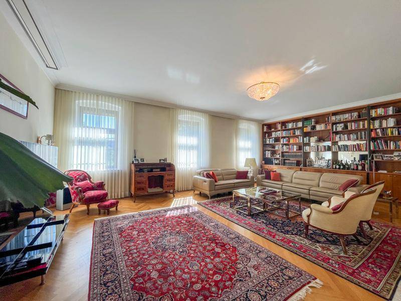 Großzügiges Wohnzimmer mit Bücherregal, Parkettboden und klassischer Einrichtung.