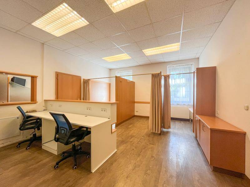 Großes Büro mit mehreren Arbeitsplätzen, Trennwänden und Laminatboden.
