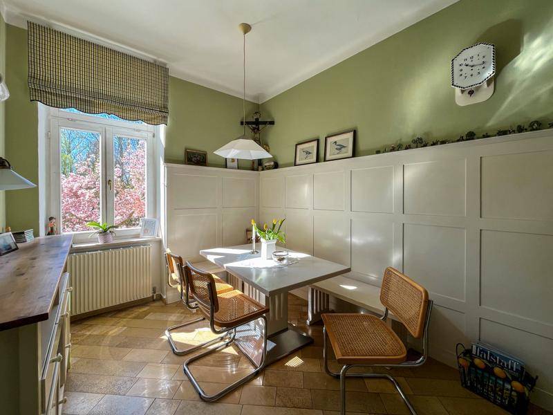 Gemütlicher Essbereich in der Küche mit Sitzbank, modernem Tisch und Blick in den blühenden Garten.