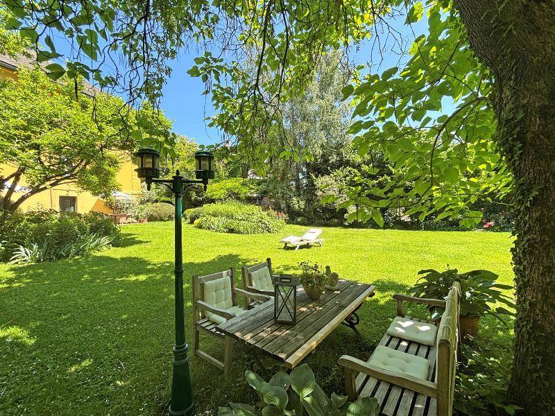 Weitläufiger Garten mit Rasenfläche, schattenspendenden Bäumen und einer rustikalen Sitzgruppe für entspannte Stunden.