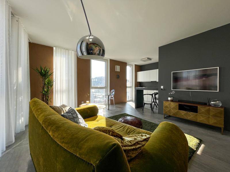 Offener Wohnbereich mit olivgrünem Sofa, Essbereich und integrierter Küchenzeile.