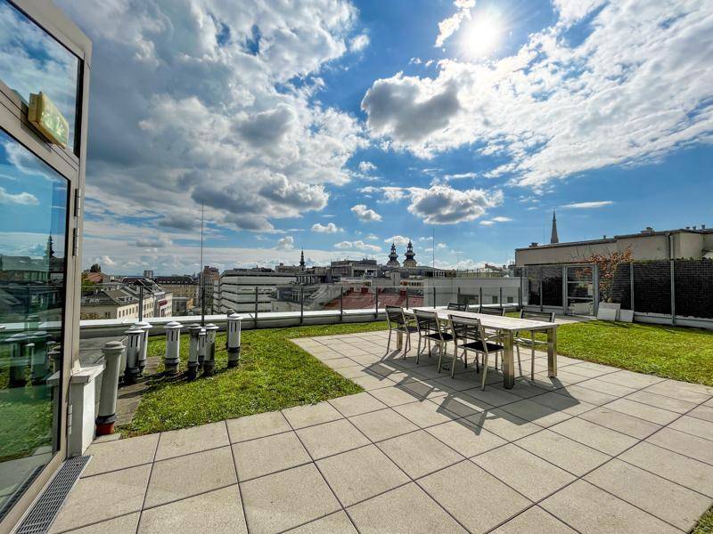 Großzügige Dachterrasse mit Sitzgelegenheiten, Rasenfläche und weitem Stadtblick.
