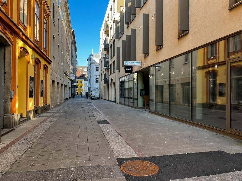 Ruhige Stadtstraße mit historischen und modernen Gebäuden unter klarem Himmel.