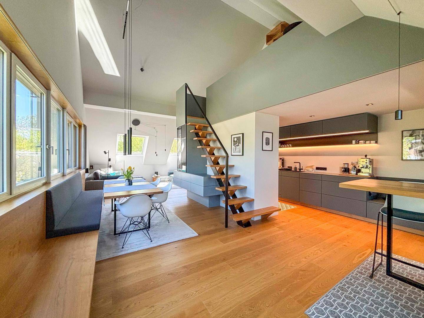 Offener Wohnbereich mit moderner Küche, Essplatz und eleganter Holztreppe.