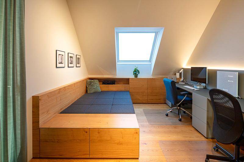 Helles Arbeitszimmer mit Schreibtisch, Tagesbett und Dachfenster unter der Schräge.
