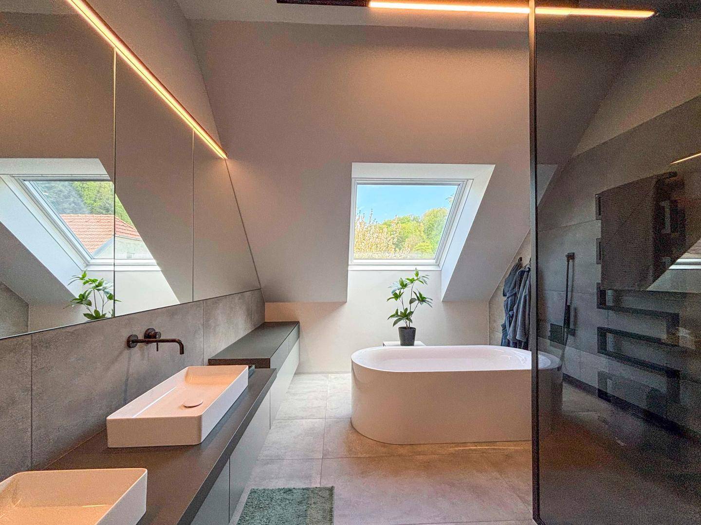 Modernes Badezimmer mit freistehender Badewanne, Doppelwaschbecken und Dachfenster.
