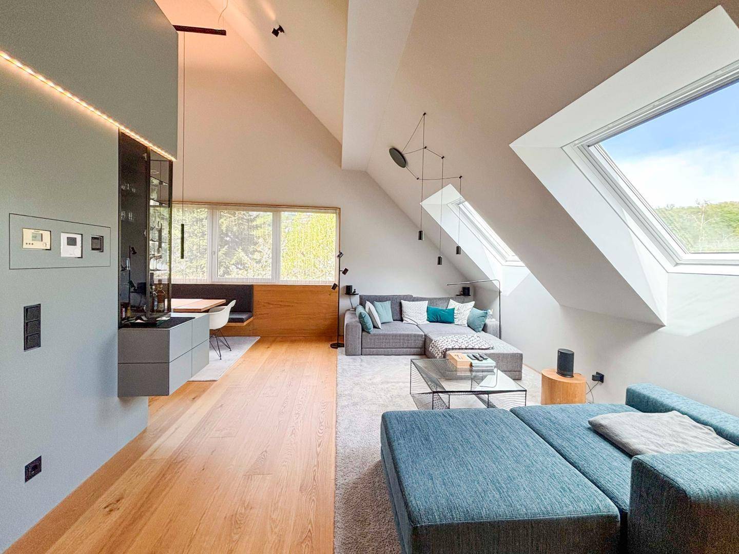 Heller Wohnbereich mit Dachschrägen, großen Dachfenstern und modernem Sofa.
