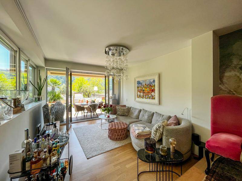 Gemütliches Wohnzimmer mit stilvollem Sofa, modernem Kronleuchter und direktem Zugang zur Terrasse.
